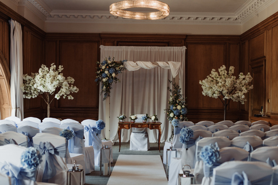 Image of blue and white themed decor for wedding ceremony, with floral decorated square arch